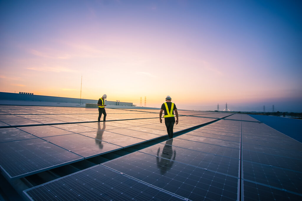 trabalhadores avaliando placas de energia solar em usina